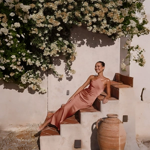 Detailed view of silky rose gold satin halter dress texture in elegant outdoor setting