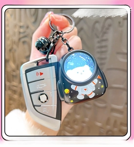 Detail showing hand holding an astronaut keychain with glowing bear pattern and black bell