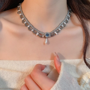 Macro shot of ethnic pearl necklace with blue gemstone and lace beadwork detail