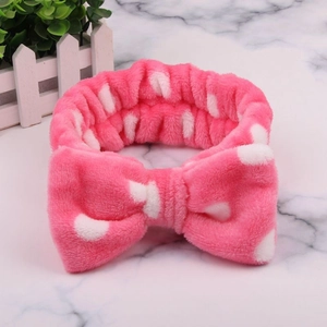Macro shot of plush pink polka dot headband texture with large soft bow detail
