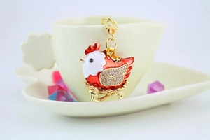 Detail of red and white hen keychain with sparkling crystals set in a yellow cup