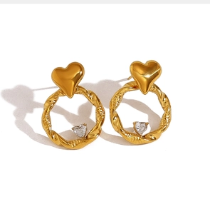 Detail of gold twisted hoop earrings with sparkling heart-shaped zircon pendants