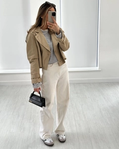 Detail of khaki cropped double-breasted trench coat paired with striped knitwear and wide pants