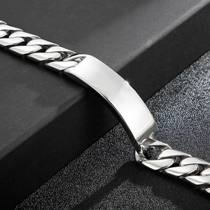Primer plano de una pulsera de cadena cubana plateada con placa pulida para grabar