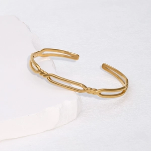 Détail d'un bracelet ouvert en acier titane doré avec ovale évidé et motif de corde torsadée