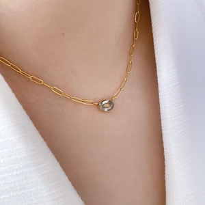 Detail of 18K gold-plated necklace with oval zircon pendant on a paperclip chain