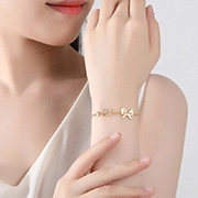 Detailed view of a gold-tone butterfly charm bracelet on a model's wrist for women