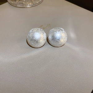 Macro shot of white spherical stud earrings with elegant wrinkled texture and matte finish