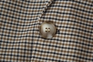 Macro shot of houndstooth wool blend fabric texture with a marbled resin button detail