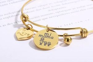 Detail of golden bangle featuring Love heart charm and Mi Mama medallion engraving