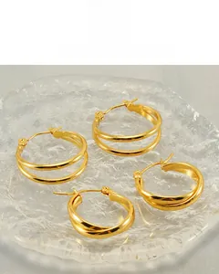 Detail view of 18K gold plated multi-layer C-shaped hoop earrings on a grey satin cloth