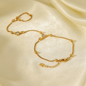 Détail d'un bracelet chaîne de main en acier inoxydable doré avec zircons en forme de cœur