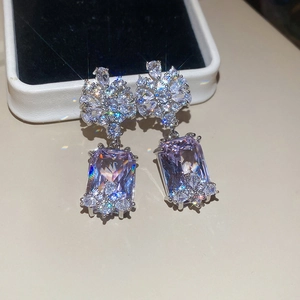 Close-up of elegant floral silver earrings with sparkling lavender rectangular stones