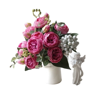 Artificial pink peony and rose bouquet with green leaves and white berries on white background