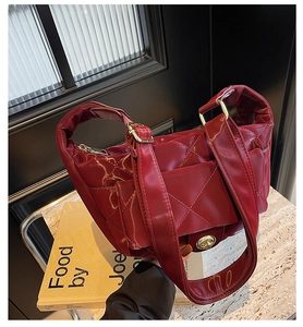 Macro detail of dark red quilted crescent bag with glossy finish and gold metal hardware