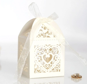 Macro shot of off-white laser-cut heart favor box with a translucent white silk ribbon