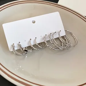 5-pair set of silver twisted hoop earrings on white display card in a ceramic dish