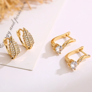 Gold leaf zircon hoop earrings and single crystal stud set against an elegant background