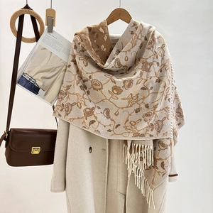 Detail of jacquard floral scarf with tassels on beige coat and wooden hanger