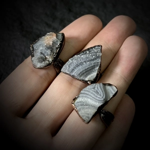 Detail of vintage copper rings featuring natural druzy agate stones and raw crystal textures