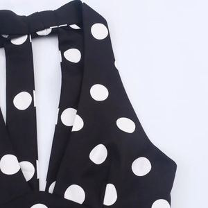 Detailed close-up of neck strap on black and white polka dot halter top garment