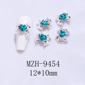 Detail of 12x10mm silver bow nail art charm with a blue heart crystal on a white nail