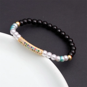 Macro shot of rainbow beaded bracelet with black onyx and crystal gold curved tube
