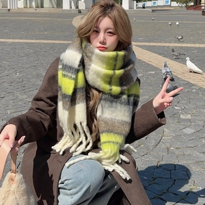 Winter striped knit scarf with fringes in yellow and grey colors on a model in urban setting
