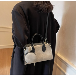 Model view of contrasting grey canvas and black leather tote bag with round pouch detail
