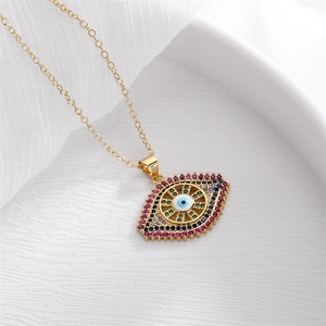 Detailed shot of gold evil eye pendant with multicolor zircon inlay on white fabric