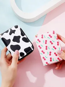 Slim accordion card holder with zipper featuring cherry and cow patterns in hand