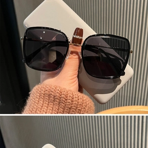 Détail de lunettes de soleil carrées avec verres noirs élégants et branches fines en métal doré