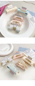 Flat lay of floral and checkered bow claw clips with pearls on a stylish desk setup