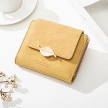 Detail of ginger yellow PU leather wallet featuring textured leaf embossing and metal clasp