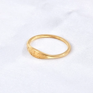 Detailed view of wide shield gold ring with engraved sunburst celestial patterns