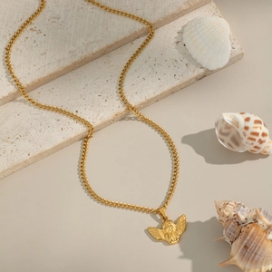 Collier à pendentif ange doré avec chaîne gourmette sur fond de pierre de travertin