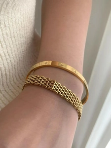 Close-up of gold plated stainless steel star engraved bangle and chunky chain bracelet