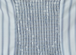 Macro detail of elastic smocked waist on light blue and white striped fabric texture