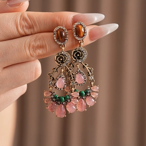 Detail of vintage flower earrings with brown cat-eye stones and pink crystal tassels