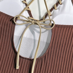 Close-up of brown ribbed swimwear with white laces and silver metallic eyelets