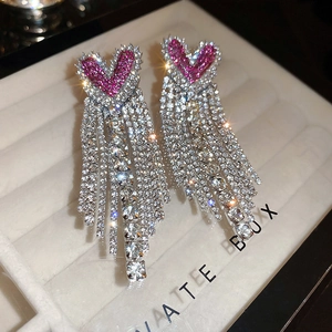 Detailed macro shot of silver tassel earrings with vibrant pink crystal heart-shaped studs