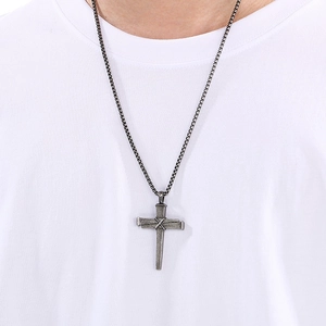 Gros plan d'un collier avec pendentif croix en clous style industriel sur t-shirt blanc