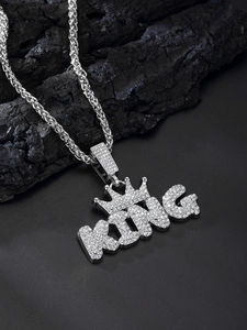 Macro detail of silver alloy KING pendant with sparkling rhinestones on charcoal