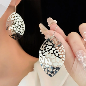 Detailed view of silver hollowed metal leaf earrings showing metallic texture and leaf veins
