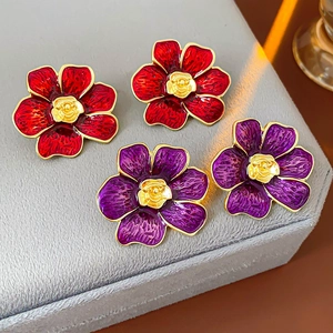 Vista macro detallada de pendientes vintage de flores en esmalte rojo y morado con oro