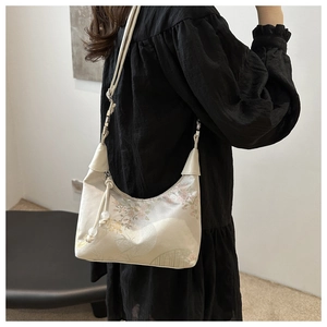 Detail of silk-texture crossbody bag with traditional Chinese floral embroidery on a model
