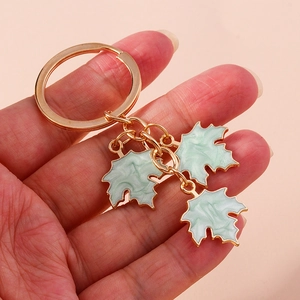 Detail of gold keychain with three light green marble-effect maple leaf pendants