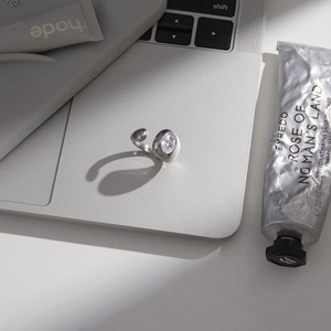 Silver adjustable stainless steel ring with a large oval zircon on a modern grey desk