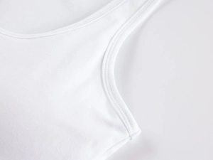 Detailed macro view of white ribbed fabric texture and fine stitching on a sports camisole