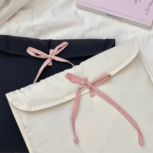 Dettaglio di custodie per laptop imbottite in nero e bianco con fiocchi rosa